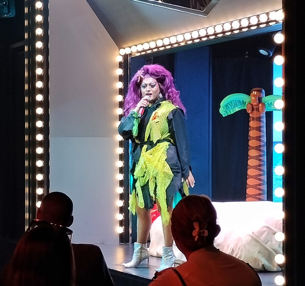 a drag queen on the stage telling jokes