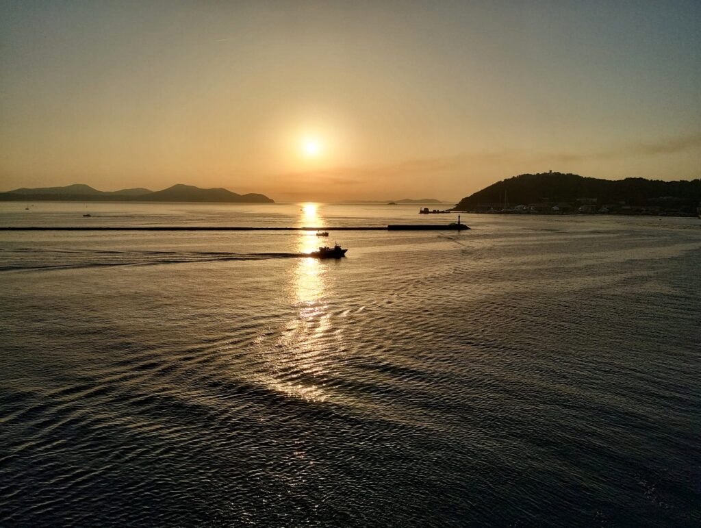 a sunset with boats in the distance